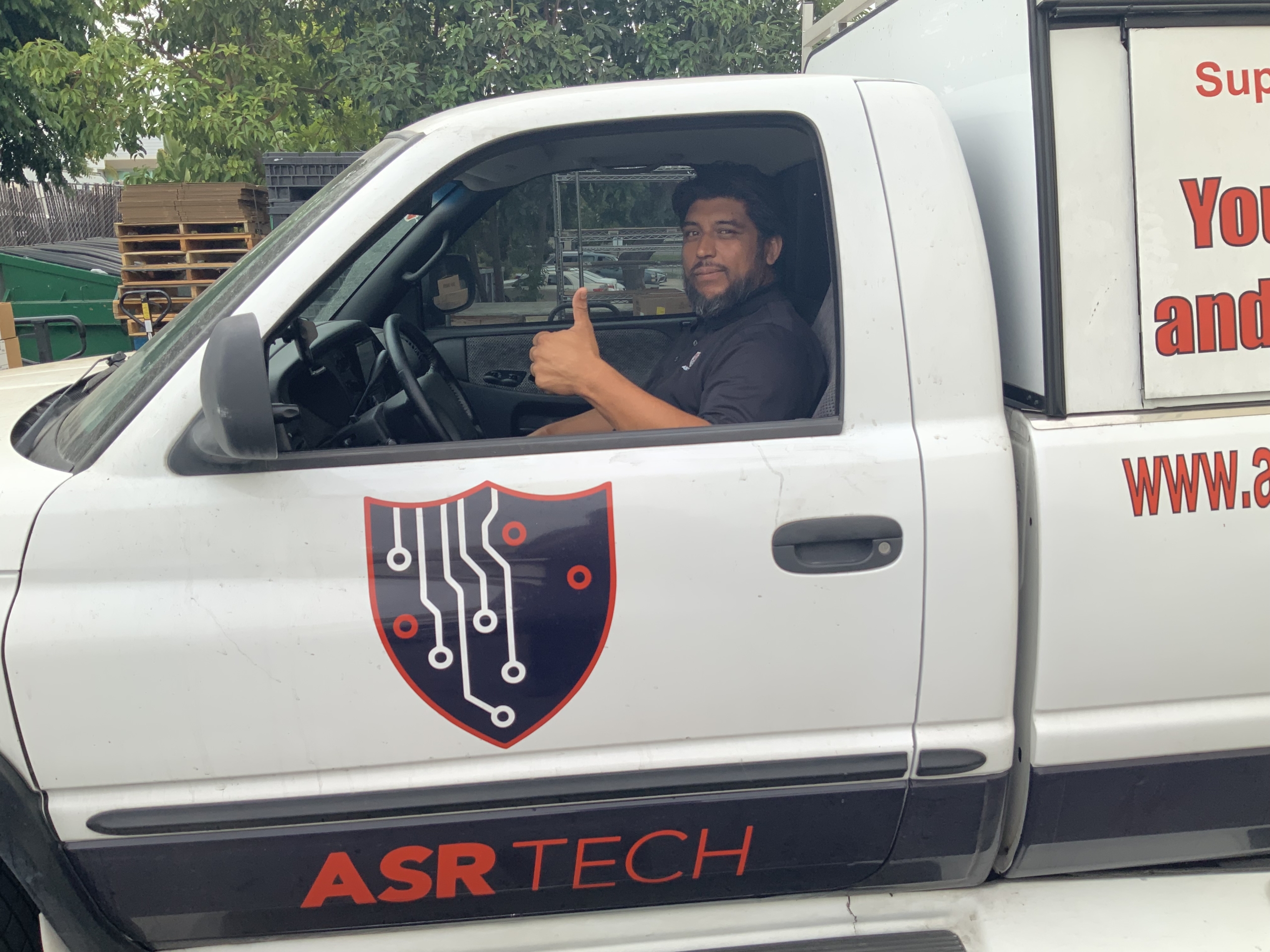 A man sitting in the driver's seat of a pickup truck, giving a thumbs up.