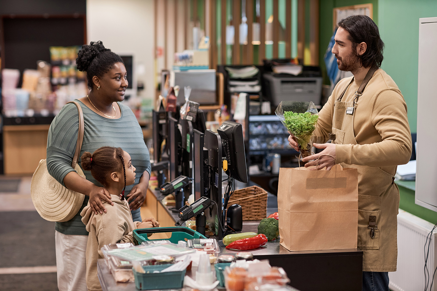 Side view portrait of young mother with little girl buying groceries in supermarket